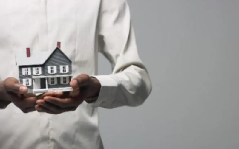 A black man holding a model of a house in his hands, Kabugu Advocates LLP – A leading law firm in Kenya providing expert legal services in litigation, real estate, employment law, and more.